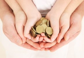 Hands of a toddler, mother and father holding coins together