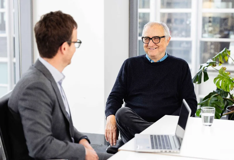 Two professional men having a friendly business discussion in a bright office setting.
