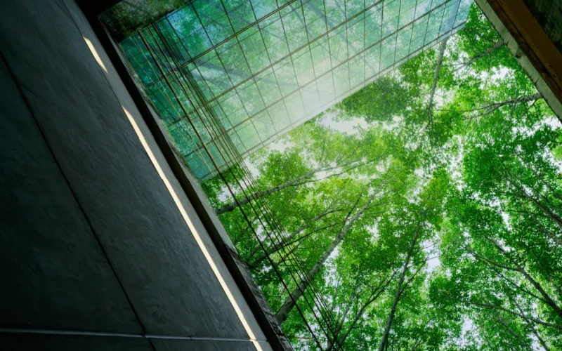 Sustainable glass building with green plants in modern cityscape — eco-friendly architecture and urban design