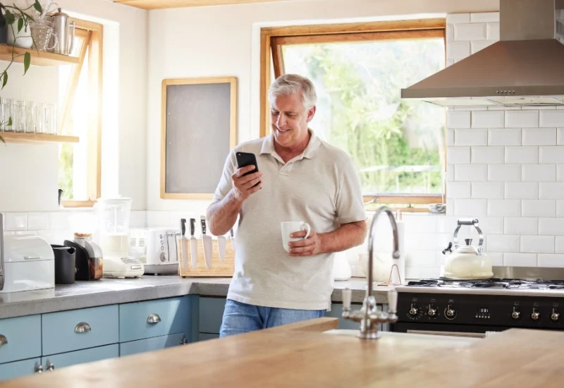 Senior man enjoying morning coffee while looking at smartphone