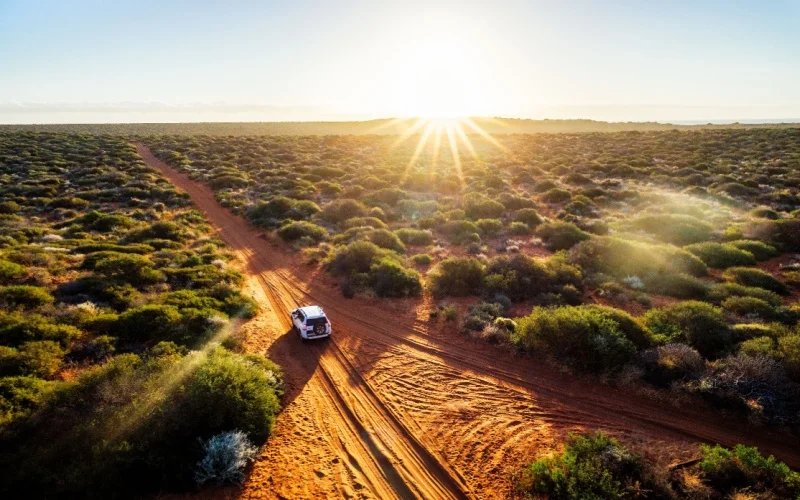 4x4 vehicle driving on red sand outback road in remote Australia rugged adventure and travel landscape
